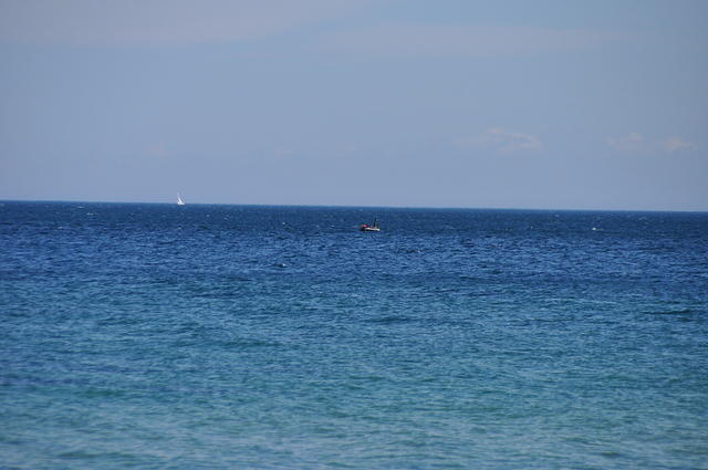 Ocean with sailboat far in the distance